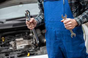 Car mechanic with car engine on background