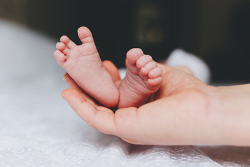 a mother's hand holding her baby's feet