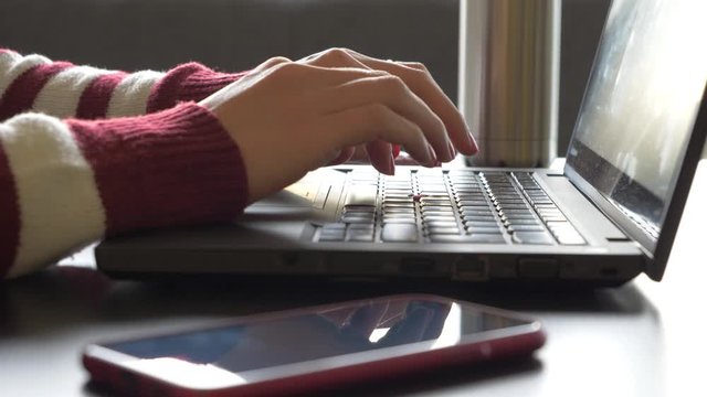 Hands of woman typing on keyboard of laptop