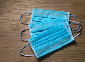 Blue protective masks lie on a wooden table