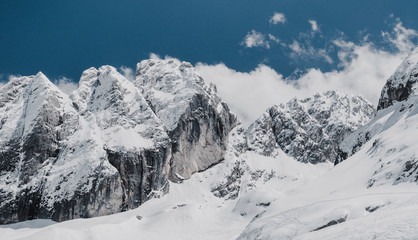 Fototapeta premium Dolomites in Italy. Beautiful landscape of snowy mountains with cloudy sky. Panorama shot of rocks and snow.