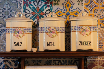 Old porcelain jars in a country house kitchen on the German island of Rügen in Germany for the storage of salt, flour and sugar. The containers are on a shelf on the wall.