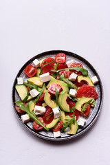 Vegetarian salad with avocado, grapefruit, tomato, feta cheese and arugula. Healthy nutrition. Selective focus