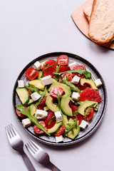 Vegetarian salad with avocado, grapefruit, tomato, feta cheese and arugula. Healthy nutrition. Selective focus
