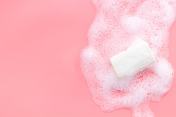 Soap bar with foam on pink background top-down copy space