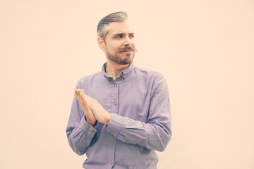 Impressed man clapping hands, applauding, looking away at copy space. Grey haired young man in blue casual shirt posing isolated over white background. Advertising concept