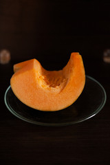 Piece of pumpkin on transparent plate and dark background. Low key