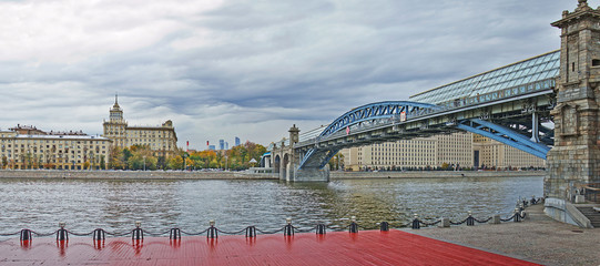 Fototapeta na wymiar Panoramic river with a large bridge and promenade in the autumn city on a cloudy day