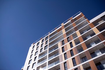 Obraz premium Exterior of new apartment buildings on a blue cloudy sky background. No people. Real estate business concept.
