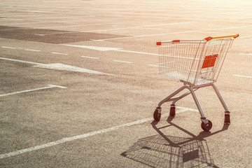 Empty single grocery cart in an empty parking lot near a supermarket at sunset. Panic during a...