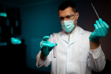 Man scientist or technologist doing experiment in a laboratory pipetting a chemical solution from a...
