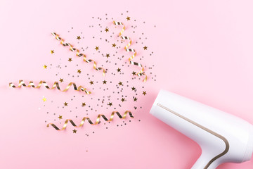Creative image of a hair dryer blow up colorful confetti. Flat lay, top view. 