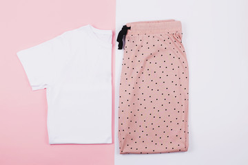A t-shirt and sweat pants on pink and white background.