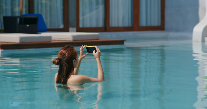 Woman use of mobile phone for take photo in swimming pool