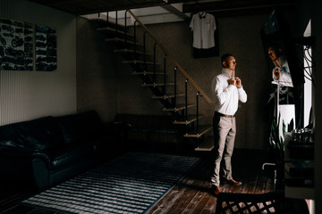 People, business,fashion and clothing concept - close up of man in shirt dressing up and adjusting tie on neck at home.