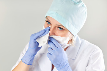 Tired female doctor wipes sweat from his face with a napkin