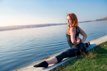 Pretty woman do the splits. morning warming-up near lake. sport active lifestyle concept