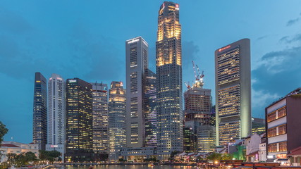 Singapore quay with tall skyscrapers in the central business district on Boat Quay day to night...