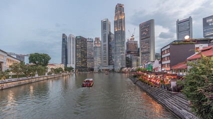 Fototapeta premium Singapore quay with tall skyscrapers in the central business district on Boat Quay day to night timelapse