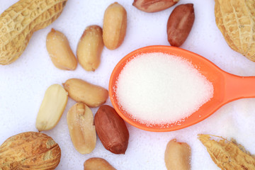 Raw peanut with salt on orange spoon, Focus on red peanut