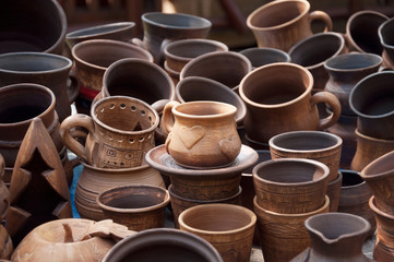 A cup of red clay with a heart. Sale at the fair a large number of diverse in style ceramic cups.