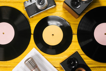 Retro vinyl record, music book, microphone and speakers on yellow flat lay background.