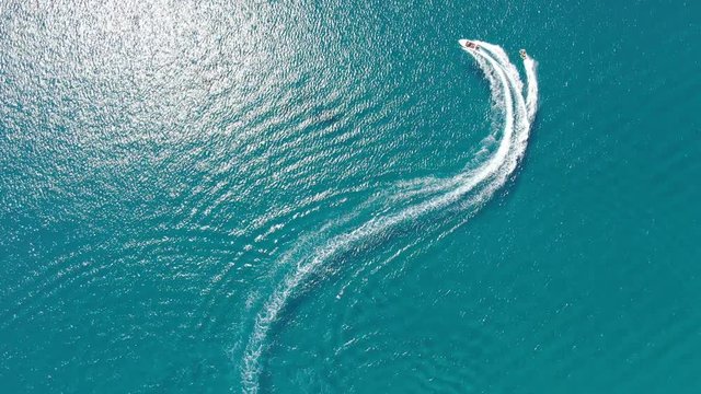 Drone footage of a speedboat pulling people on a tube.