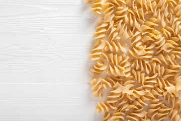 Uncooked dried pasta on wooden white background. Space for text. Top View.