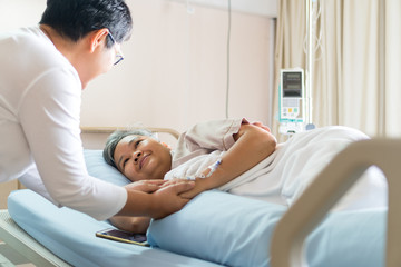 Happy Woman Visits Best friends holding hands for recovering that sick lying in Hospital, looking...