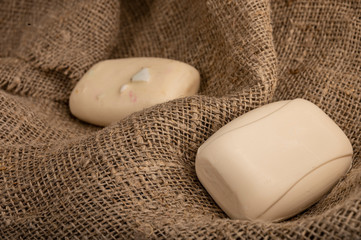 Two pieces of toilet soap on a background of coarse-textured fabric. Close up. Clean hands is the...
