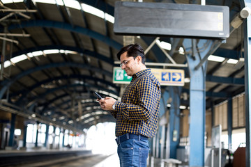 Man using mobile phone at railroad station platform