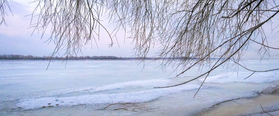 Fototapeta na wymiar Winter landscape at dawn, riverbank of a frozen ice.