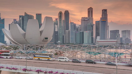 Aerial view of sunset over Helix Bridge and Bayfront Avenue with traffic timelapse at Marina Bay, Singapore