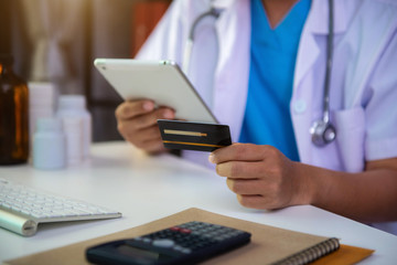 Doctor hold credit cards, conduct financial transactions via tablets and data documents, put on the desk in the morning.