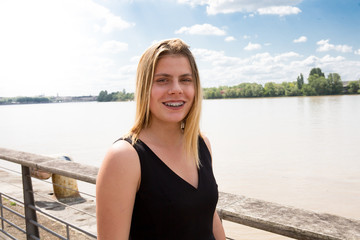 Young blonde woman smiling with braces in city riverside