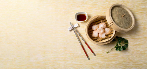 Fototapeta na wymiar HAR GOW in bamboo steamer with sauces and chopsticks. Chinese Traditional cuisine concept. Dumplings Dim Sum in bamboo steamer with text copy space. Asian food background