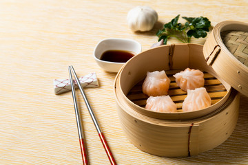 HAR GOW in bamboo steamer with sauces and chopsticks. Chinese Traditional cuisine concept. Dumplings Dim Sum in bamboo steamer with text copy space. Asian food background