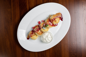 Cheesecakes with fruits on a white plate with sweet sauce.