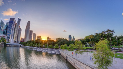 Obraz premium Sunset over Singapore skyscrapers skyline with white Anderson Bridge near esplanade park timelapse.