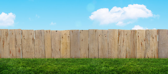 wooden garden fence with spring grass at backyard