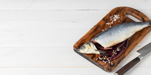Salted herring on a cutting board, the process of making Haringhandel herring sandwich. Close-up, copy space for text. Country style