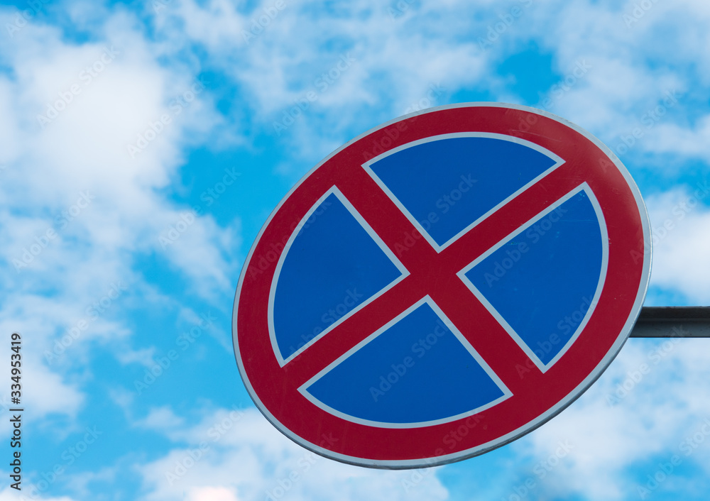 Wall mural no stopping road sign against a blue sky with white clouds.