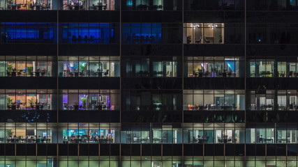 Fototapeta na wymiar Modern office building with big windows at night timelapse, in windows light shines