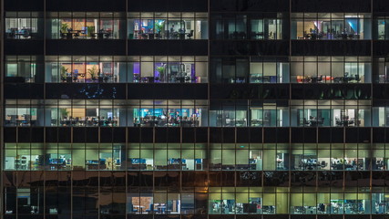 Fototapeta na wymiar Modern office building with big windows at night timelapse, in windows light shines
