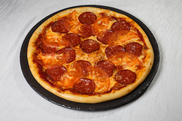 Italian pizza on gray plates on a white plate with spices and seasonings vegetables and meat.