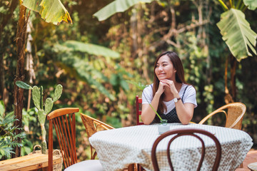 Portrait image of a beautiful asian woman sitting in the outdoors with nature background