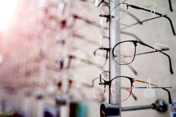 Many glasses on a stand. Showcase with glasses in modern ophthalmic store. Closeup.