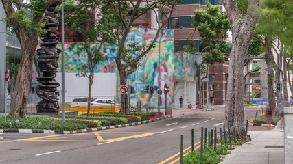 Battery Road avenue with traffic and surrounded by green trees in downtown timelapse, Singapore