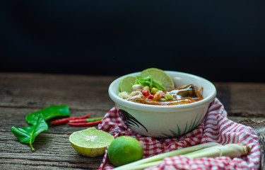 Sardines in tomato sauce with lemongrass, kaffir lime leaves, chilies, lime on wooden table.