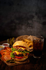 Fresh and juicy hamburger. Cheese burger with beef or bacon, patty tomato, onion ring and sparkling water or beer. Junk food to eat.